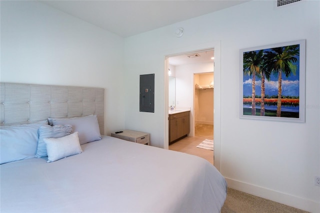 bedroom with ensuite bathroom, a spacious closet, light carpet, and electric panel