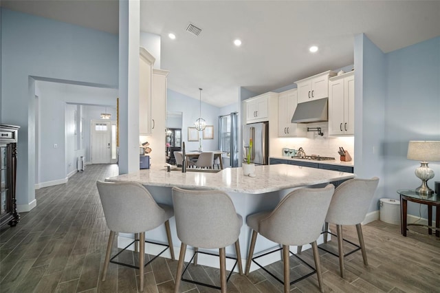 kitchen featuring hanging light fixtures, stainless steel appliances, tasteful backsplash, white cabinets, and kitchen peninsula