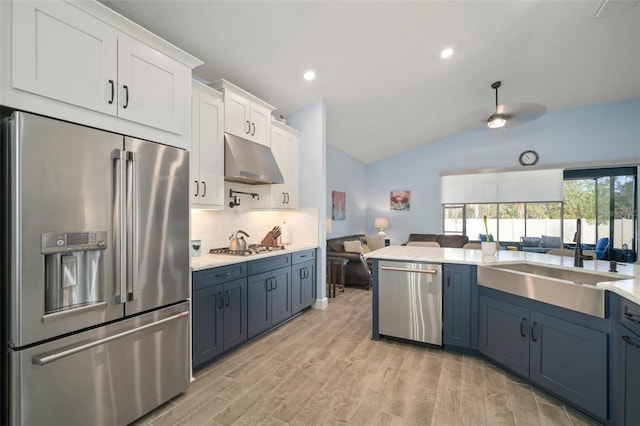 kitchen with blue cabinets, tasteful backsplash, appliances with stainless steel finishes, light hardwood / wood-style floors, and white cabinets