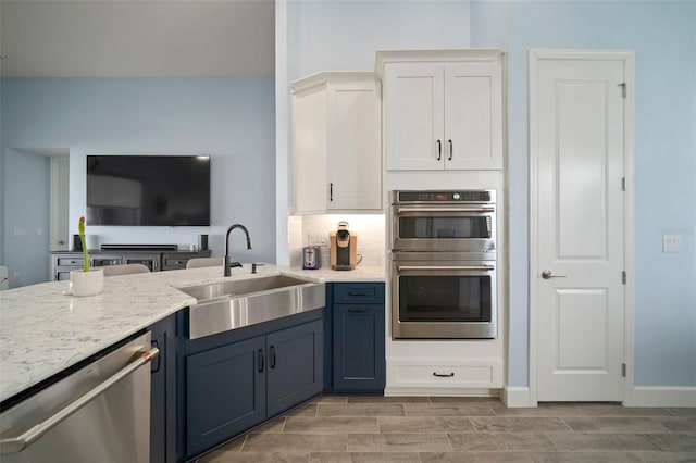 kitchen with blue cabinets, sink, tasteful backsplash, appliances with stainless steel finishes, and white cabinets