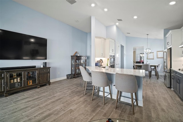 kitchen featuring decorative light fixtures, white cabinets, stainless steel appliances, an inviting chandelier, and light hardwood / wood-style flooring