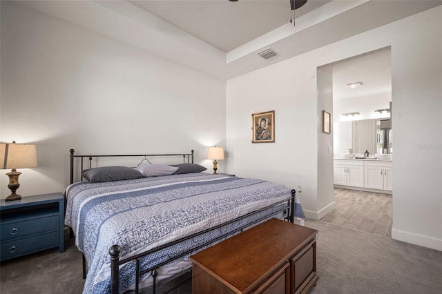 bedroom with connected bathroom, sink, and carpet