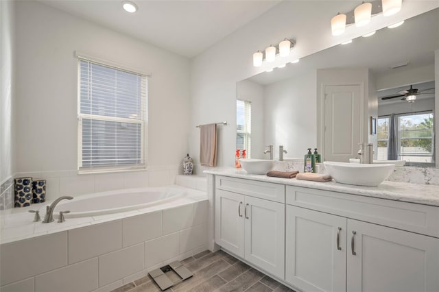 bathroom with vanity, a wealth of natural light, tiled bath, and ceiling fan