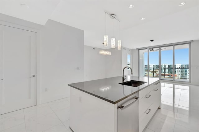 kitchen with sink, white cabinetry, floor to ceiling windows, an island with sink, and decorative light fixtures