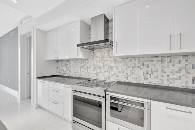 kitchen with white cabinets, decorative backsplash, stainless steel range with electric stovetop, and wall chimney exhaust hood