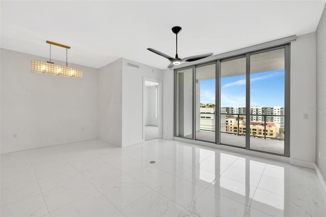 unfurnished room with ceiling fan with notable chandelier and floor to ceiling windows