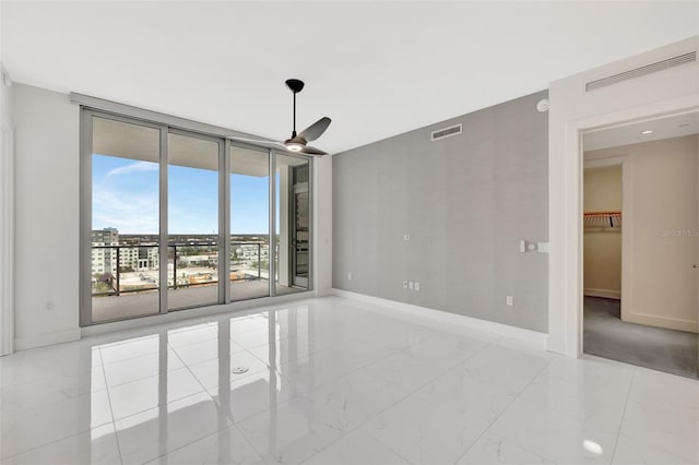 spare room featuring ceiling fan and a wall of windows