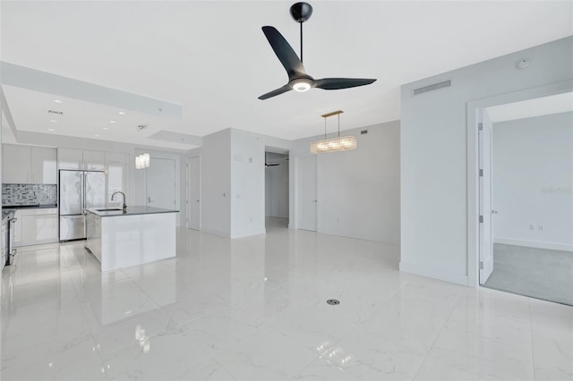 unfurnished living room with ceiling fan with notable chandelier and sink