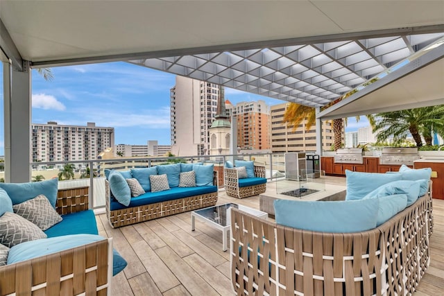 wooden terrace with exterior kitchen, area for grilling, an outdoor living space with a fire pit, and a pergola