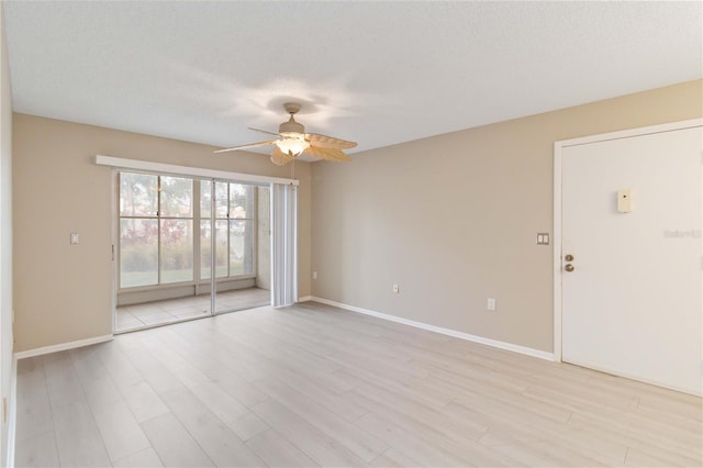 spare room with light wood-style floors, ceiling fan, baseboards, and a textured ceiling