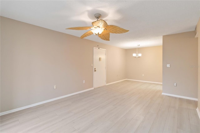 empty room featuring baseboards, a textured ceiling, light wood finished floors, and ceiling fan with notable chandelier