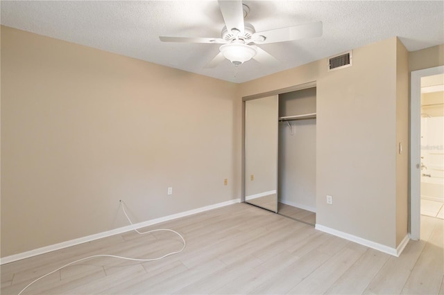 unfurnished bedroom with a textured ceiling, a closet, wood finished floors, and visible vents