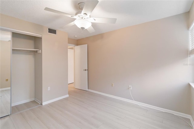 unfurnished bedroom with baseboards, visible vents, a ceiling fan, light wood-style flooring, and a closet