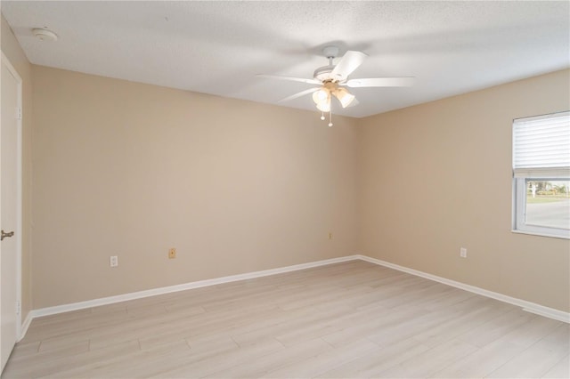 spare room featuring light wood-style flooring, baseboards, ceiling fan, and a textured ceiling