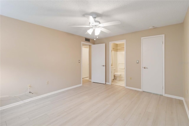 unfurnished bedroom with light wood finished floors, visible vents, ensuite bathroom, a textured ceiling, and baseboards