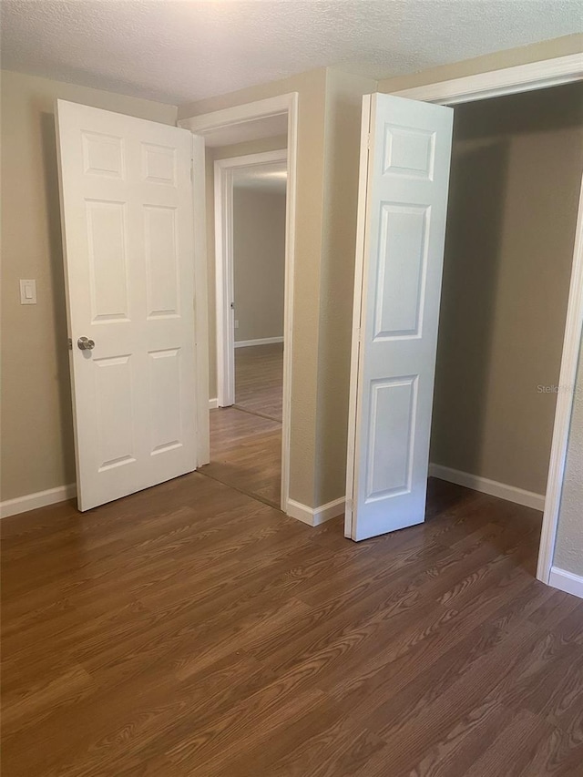 unfurnished bedroom with dark hardwood / wood-style flooring and a textured ceiling