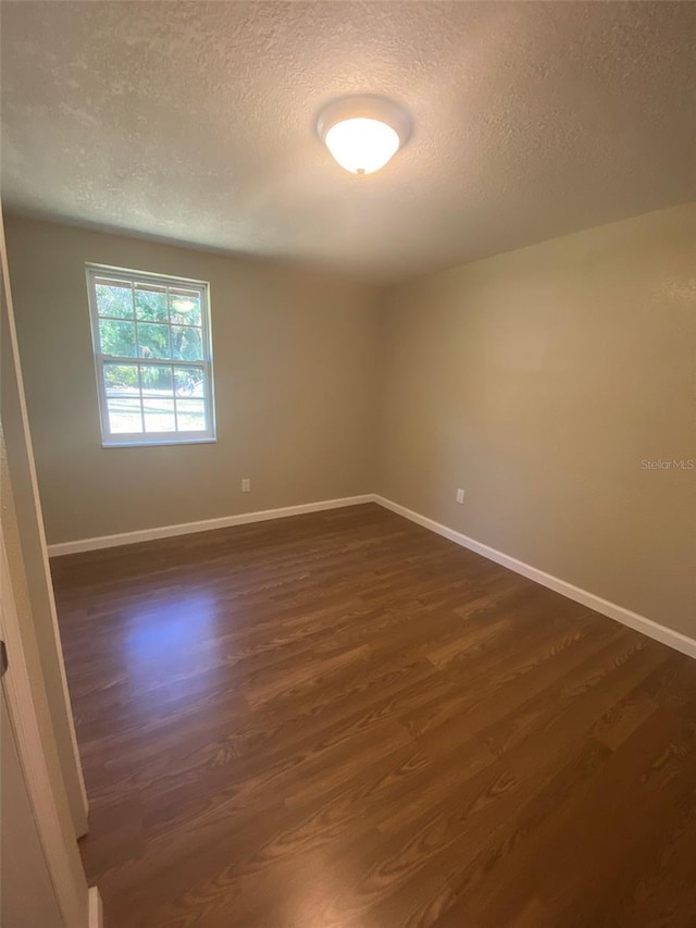 unfurnished room with a textured ceiling and dark hardwood / wood-style floors