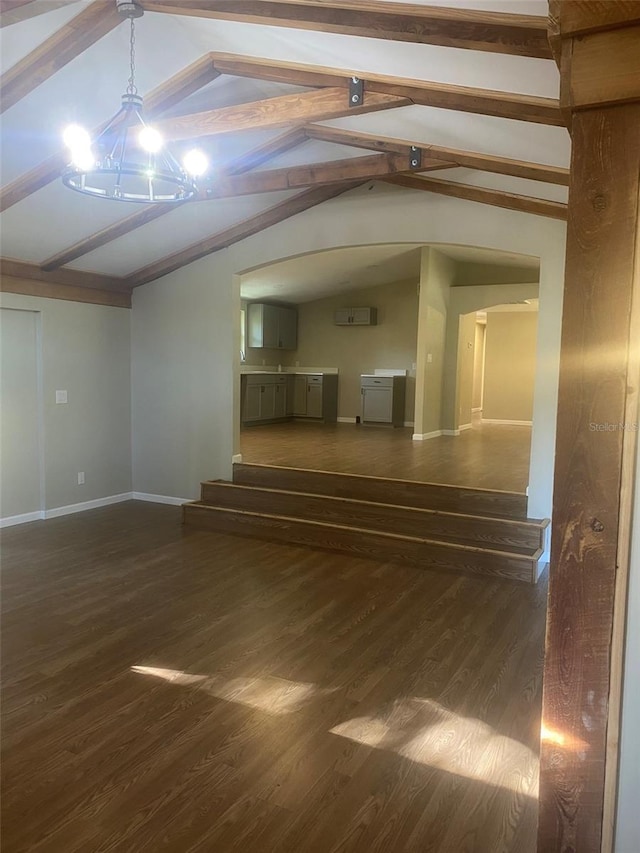 unfurnished living room with vaulted ceiling with beams, dark wood-type flooring, and an inviting chandelier