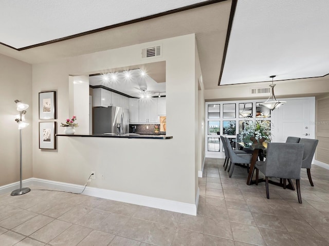 kitchen with stainless steel refrigerator with ice dispenser, tasteful backsplash, light tile patterned floors, white cabinetry, and hanging light fixtures