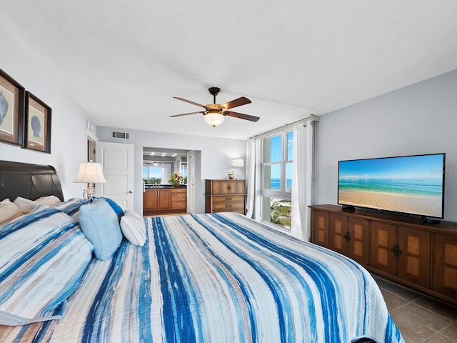 bedroom featuring tile patterned floors, ceiling fan, and a textured ceiling