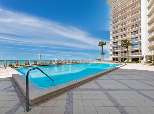 view of swimming pool featuring a patio and a water view