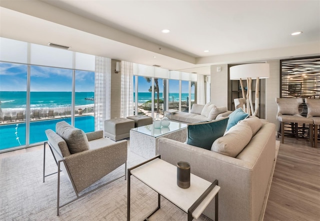 living room featuring a water view, a view of the beach, and hardwood / wood-style flooring