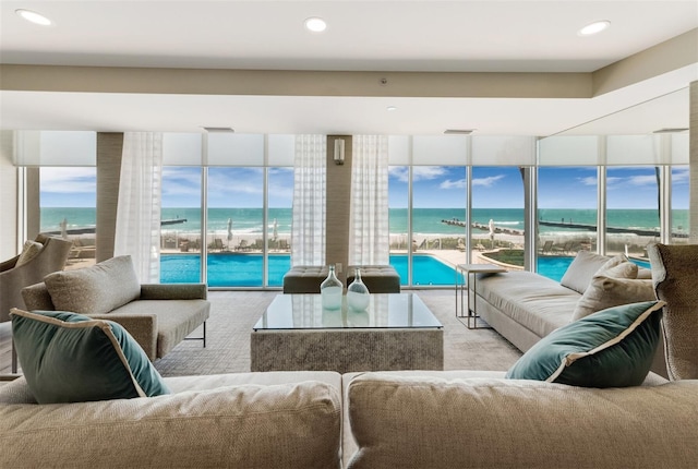 living room with a water view, light colored carpet, and a view of the beach