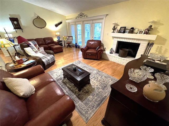 living room featuring wood-type flooring, a brick fireplace, and a textured ceiling