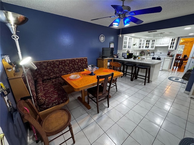 tiled dining space featuring ceiling fan and a textured ceiling