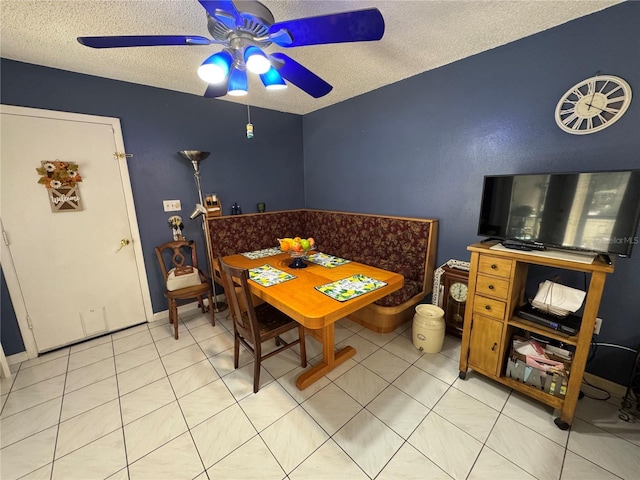 tiled dining area with ceiling fan and a textured ceiling