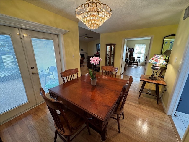 dining area with french doors, an inviting chandelier, light hardwood / wood-style flooring, and a textured ceiling