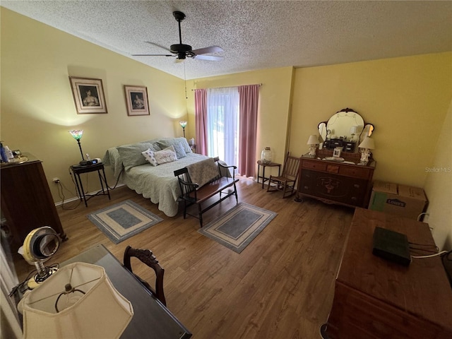 bedroom with ceiling fan, lofted ceiling, hardwood / wood-style floors, and a textured ceiling