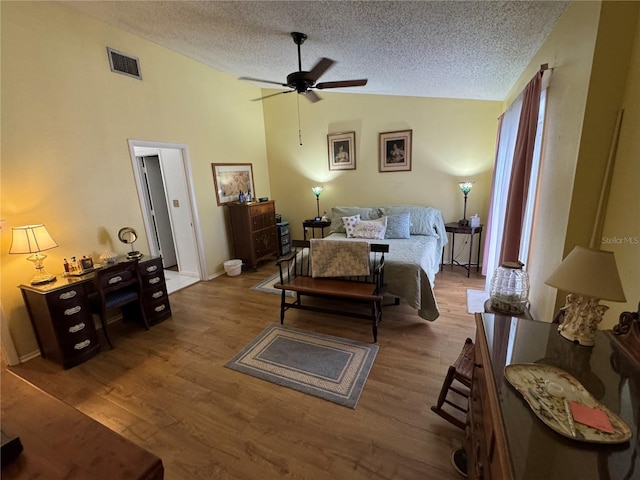 bedroom featuring ceiling fan, lofted ceiling, a textured ceiling, and light hardwood / wood-style floors