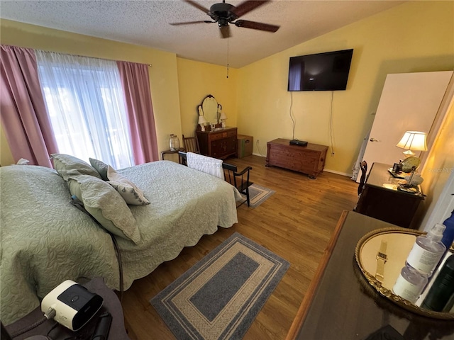 bedroom with hardwood / wood-style flooring, ceiling fan, lofted ceiling, and a textured ceiling