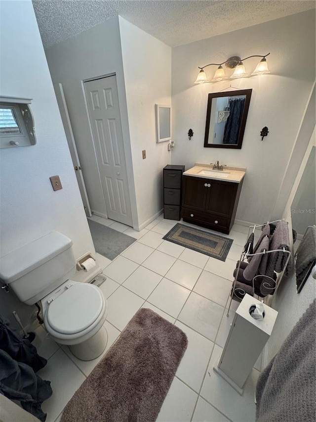 bathroom featuring tile patterned flooring, vanity, toilet, and a textured ceiling