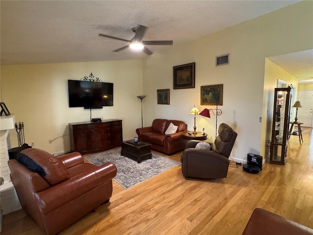 living room with hardwood / wood-style flooring, ceiling fan, and a textured ceiling