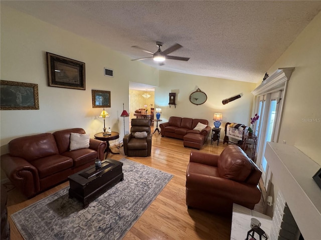 living room featuring ceiling fan, vaulted ceiling, hardwood / wood-style floors, and a textured ceiling