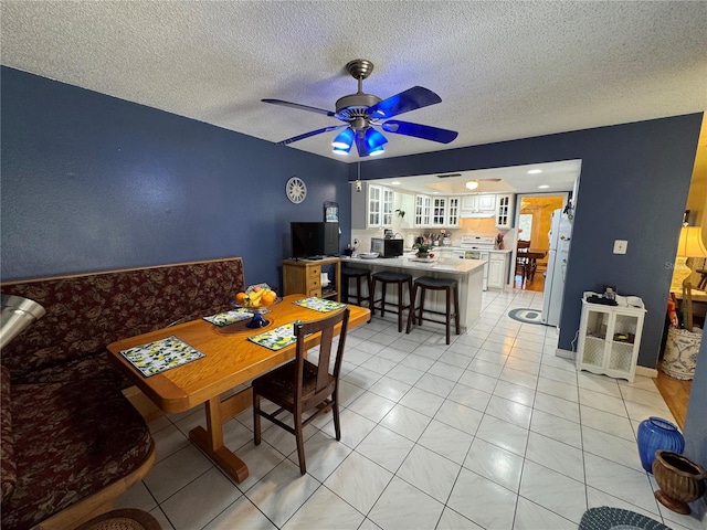 dining area with a textured ceiling, ceiling fan, and light tile patterned flooring