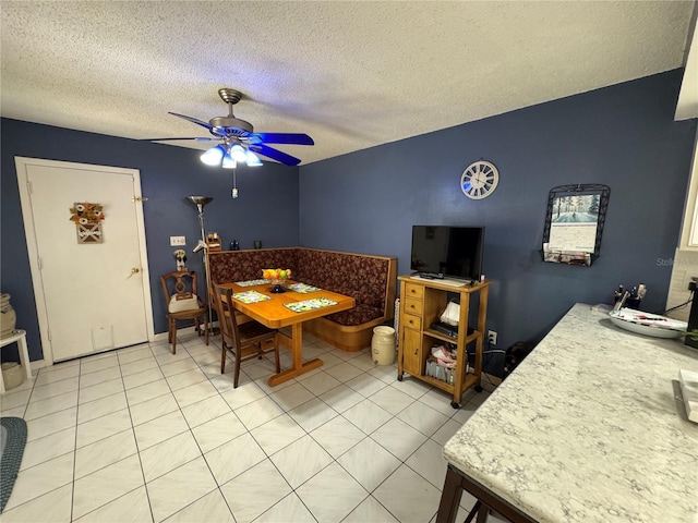 tiled dining area with a textured ceiling and ceiling fan