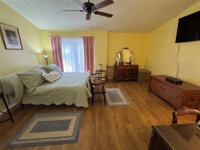 bedroom with lofted ceiling, hardwood / wood-style floors, a textured ceiling, and ceiling fan