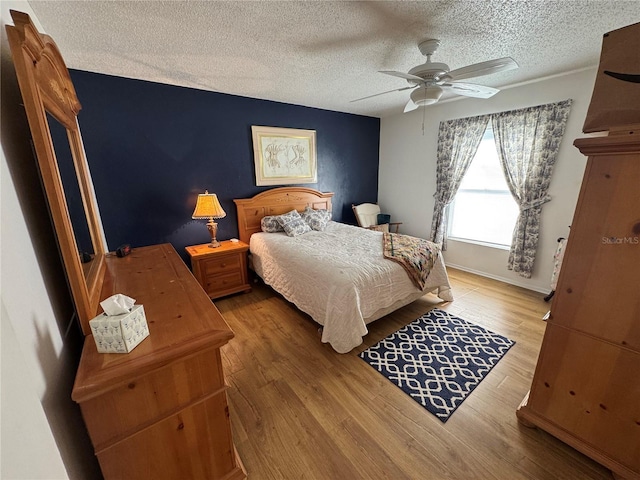 bedroom featuring ceiling fan, wood-type flooring, and a textured ceiling