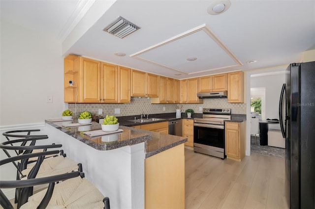 kitchen with sink, a kitchen breakfast bar, kitchen peninsula, dark stone countertops, and appliances with stainless steel finishes