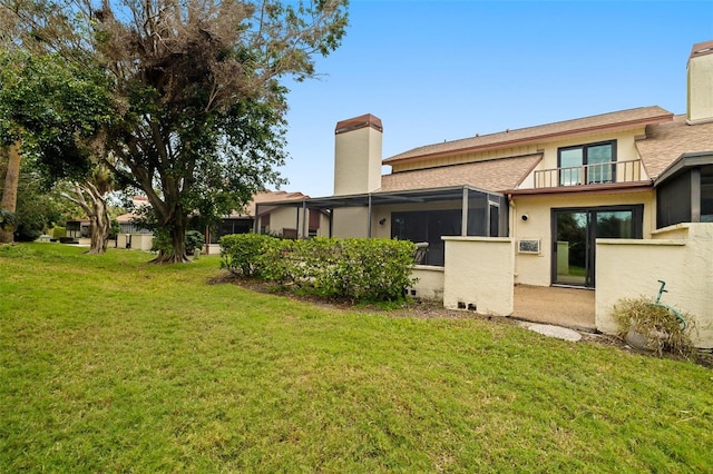 rear view of property with a yard, a balcony, and a sunroom