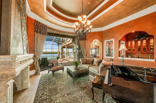 living area with a notable chandelier, a water view, crown molding, and a tray ceiling