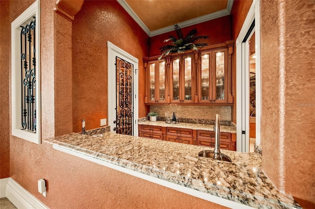 interior space with light stone counters, sink, and ornamental molding