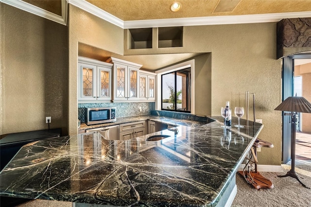 kitchen with kitchen peninsula, ornamental molding, appliances with stainless steel finishes, and tasteful backsplash