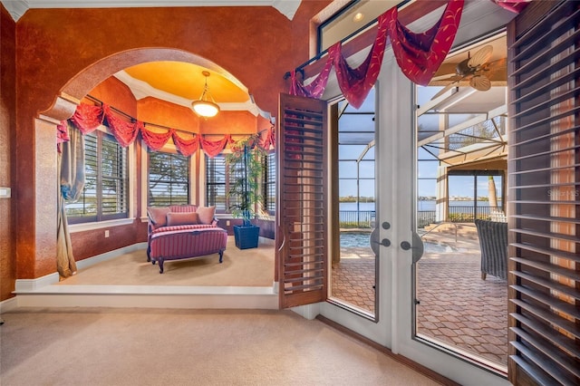 doorway with carpet flooring, french doors, ornamental molding, ceiling fan, and a water view