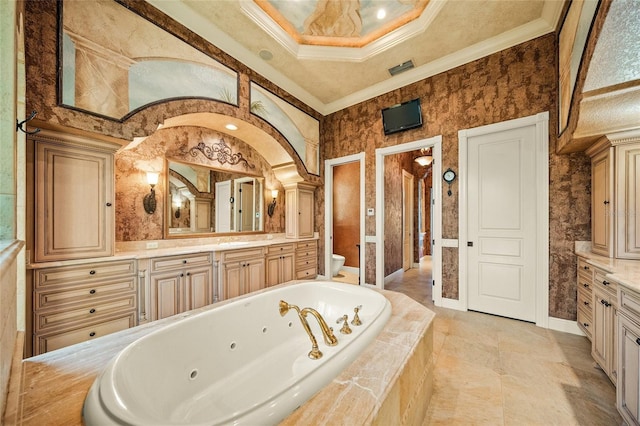 bathroom with vanity, toilet, ornamental molding, and tiled bath