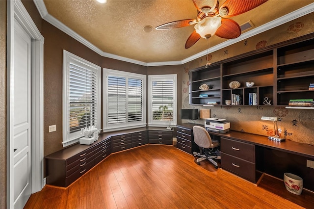 unfurnished office featuring ceiling fan, crown molding, wood-type flooring, a textured ceiling, and built in desk