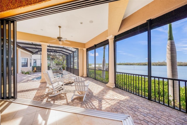 unfurnished sunroom with ceiling fan and a water view